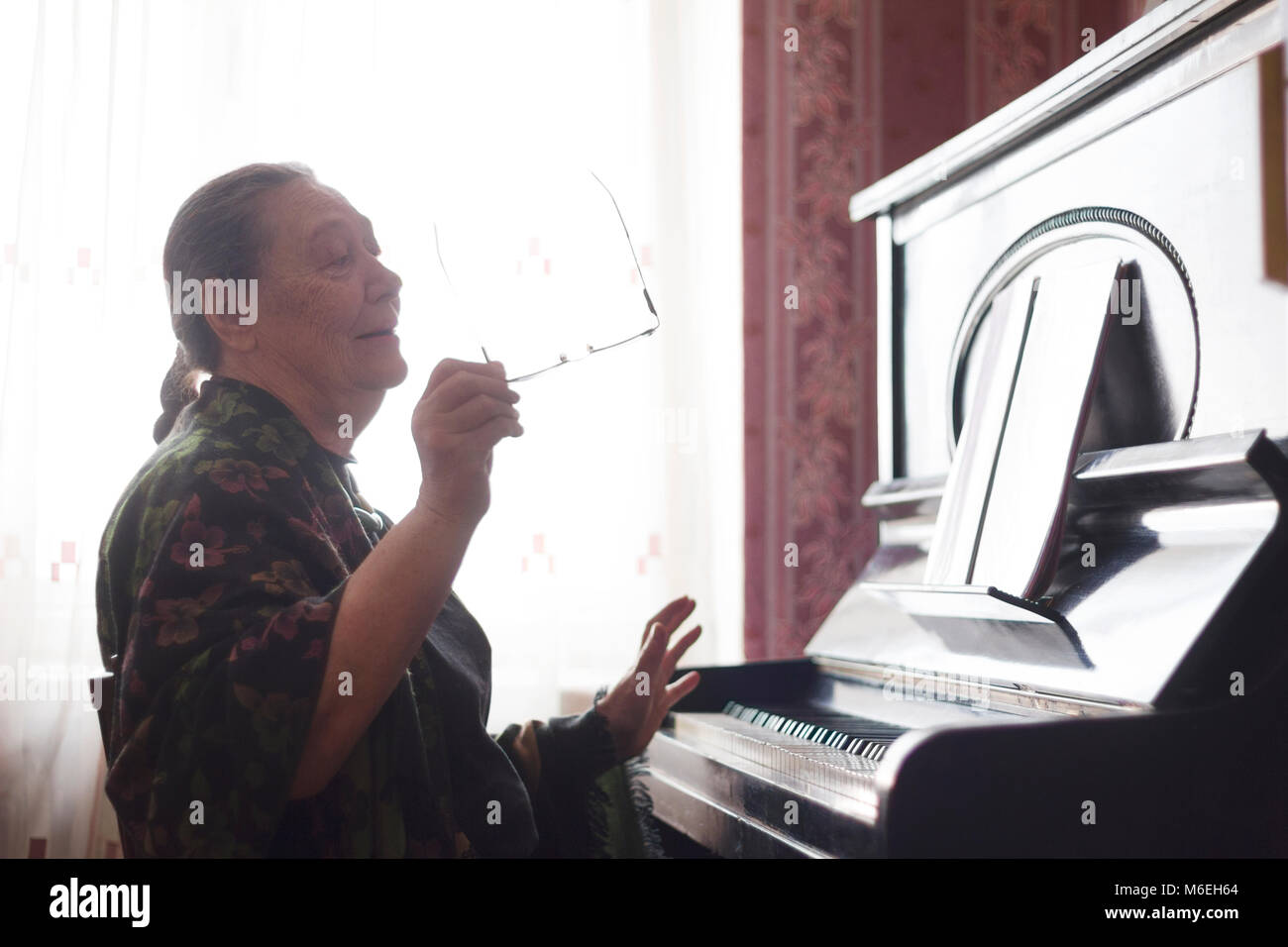Die alte Dame sitzt vor einem Klavier und singen ein Lied in einem Notebook suchen Stockfoto
