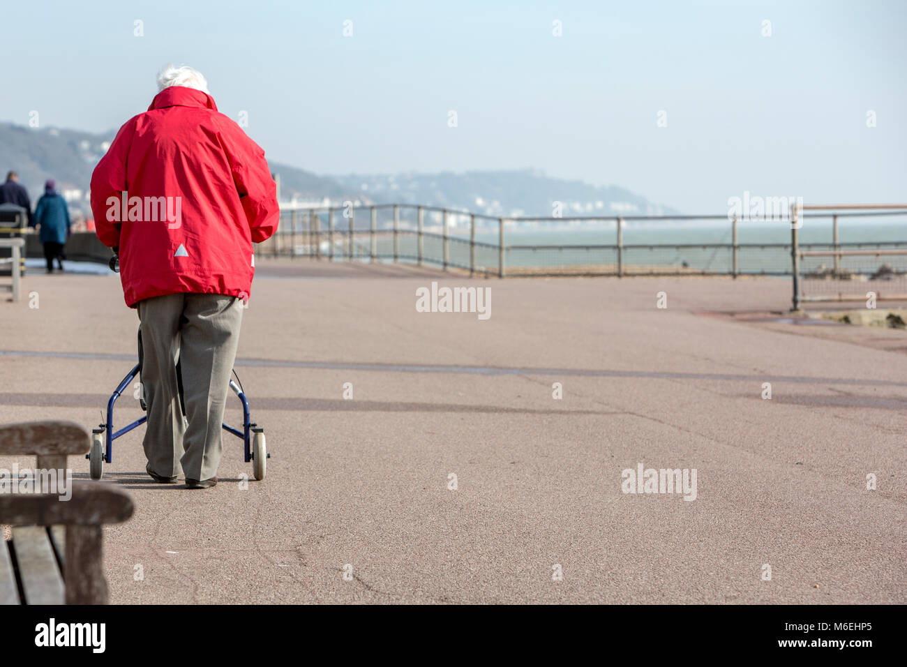 Ein alter Mann mit einer Gehhilfe auf einem Spaziergang am Meer Stockfoto