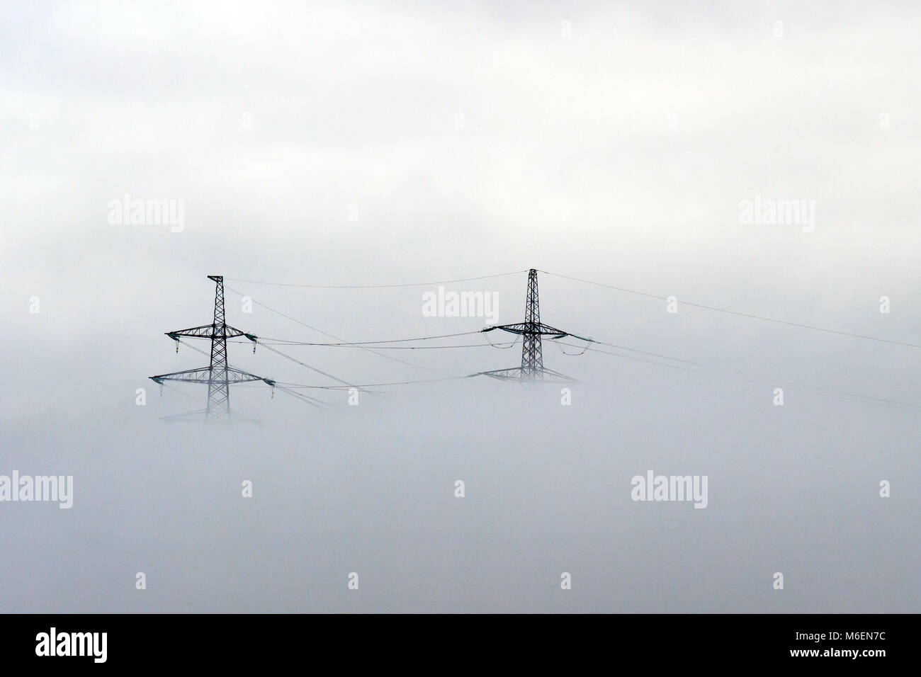 Strommasten im Nebel Stockfoto