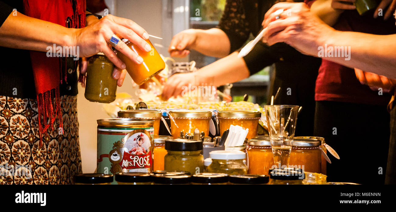 Hände reichen Gläser mit Marmelade über einen dicht gedeckten Tisch, ein Etikett lautet „Mrs. Rose“ als Hersteller – eine HandelsSzene auf dem ersten Grevenbroicher „Schwarzen Markt“, einem Tauschmarkt für hausgemachte Lebensmittel an der Kochschule „Peter sei selig – Genusspunkt Küche“, Auf der Schanze, Grevenbroich, Nordrhein-Westfalen, Deutschland, am 13. November 2016. Händler kamen aus so weit entfernten Städten wie Neuss, Bonn und Mönchengladbach, um Marmeladen, Chutneys, Quittenbrot und andere hausgemachte Waren zu tauschen. Stockfoto