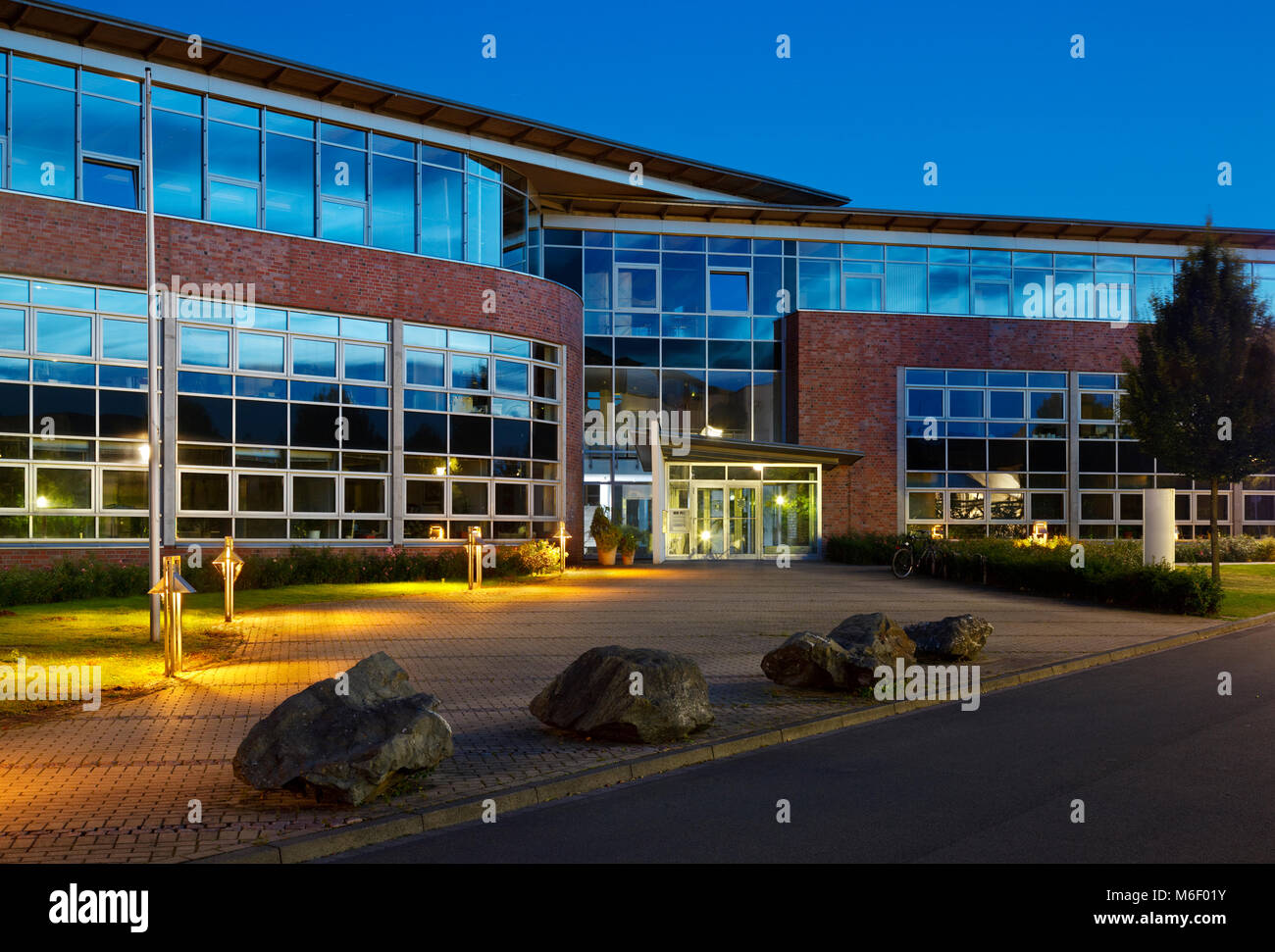 Ein modernes Bürogebäude mit Glasfassaden und Beleuchtung in der blauen Stunde. Stockfoto