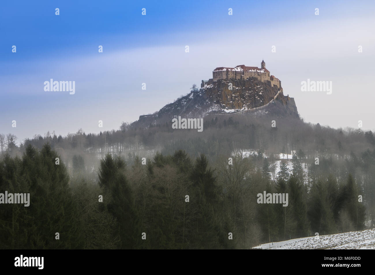 Blauen Himmel über die Riegersburg und neblig, kalt und gruseligen Wald unten Stockfoto