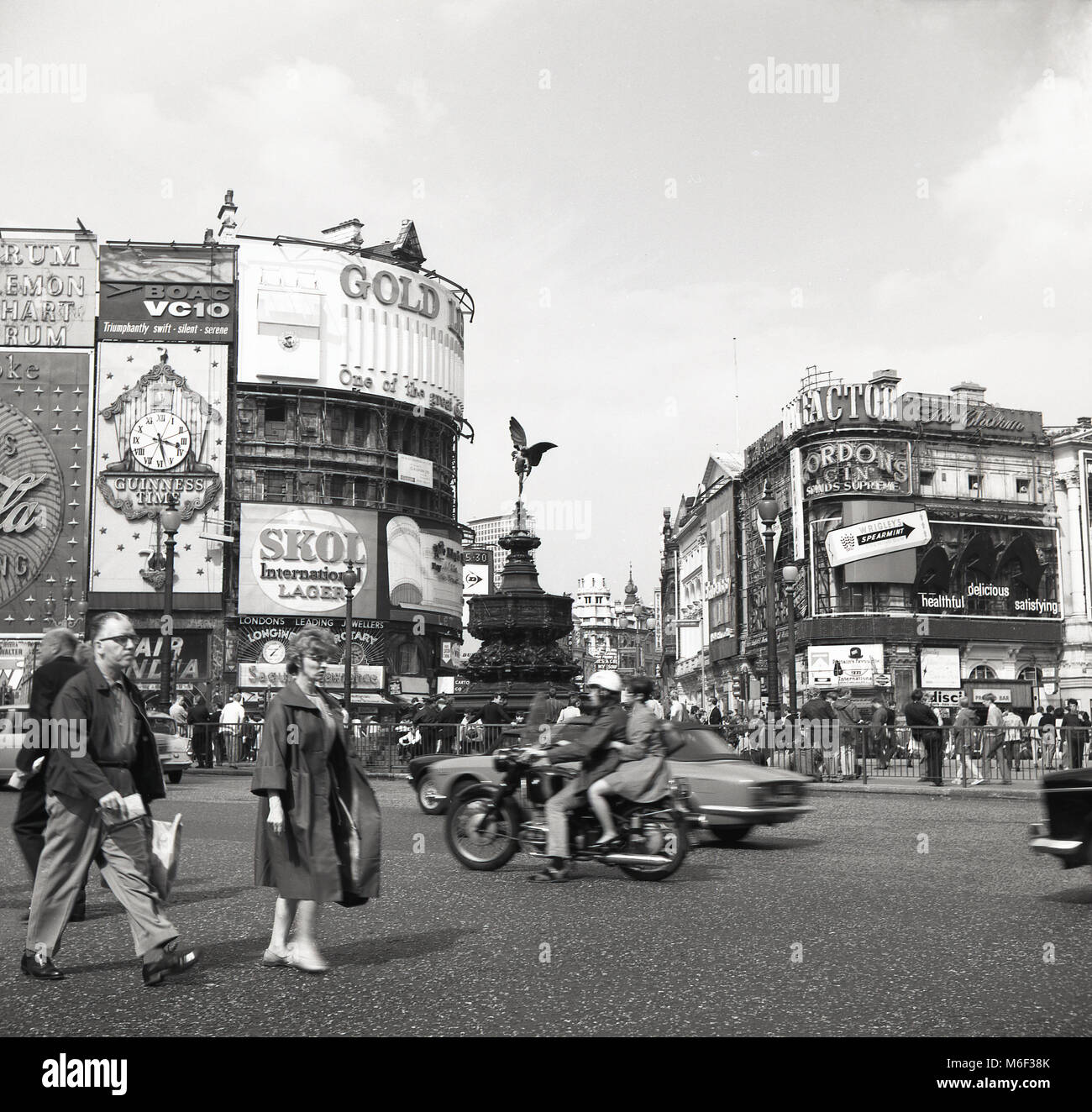 1960, historische Abbildung, die den berühmten Adverising Anschlagtafeln am Kreisverkehr an einer belebten Piccadilly Circus, London, England, mit Motor Verkehr um die shaftsbury Memorial Fountain - häufig, aber fälschlicherweise als Eros bekannt - in der Mitte der Kreuzung. Stockfoto