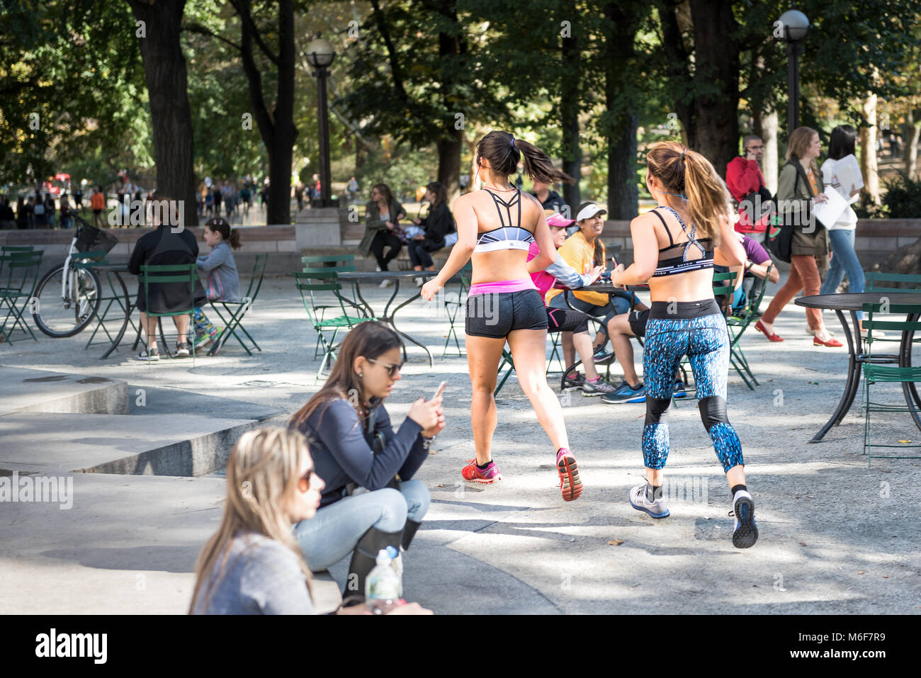 New York City, USA - Oktober 28, 2017: Midtown Manhattan mit Menschen zwei junge Mädchen Frauen laufen, joggen, Sport treiben, im Central Park von Stühlen, ta Stockfoto