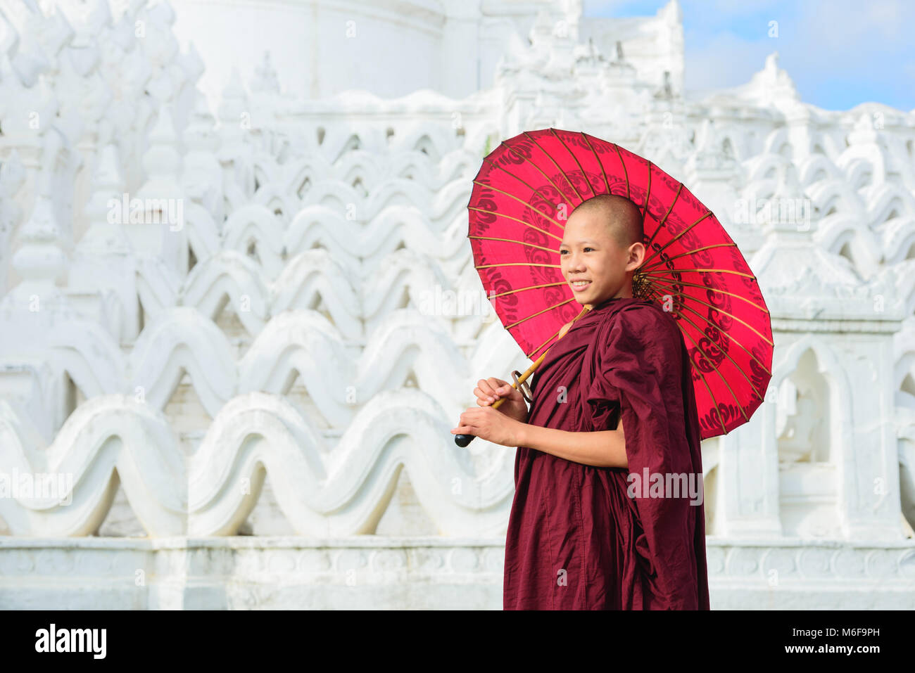 MANDALAY, Myanmar, - Dezember 11, 2017: Unbekannter Asiatische junge Mönch halten roten Sonnenschirme am Mya Thein Tan Mingun Pagode in Mandalay, Myanmar. Stockfoto