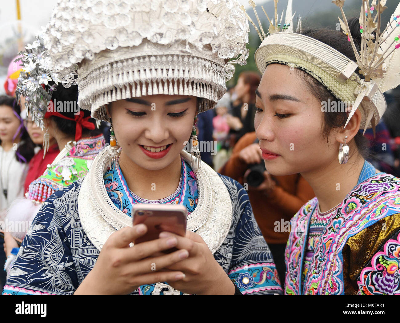 Rongshui, China Guangxi Zhuang autonomen Region. 3 Mär, 2018. Ein Mädchen von Miao ethnische Gruppe mit ihrem Mobiltelefon Bilder, die während der 'pohui' Festival in Xiangfen Township von Rongshui Miao autonomen County, South China Guangxi Zhuang autonomen Region, 3. März 2018 zu senden. Mehr als 10.000 Einwohner von Miao und Dong ethnischen Gruppen aus den umliegenden Townships am Samstag das traditionelle Fest zu feiern. Credit: Zhang Ailin/Xinhua/Alamy leben Nachrichten Stockfoto