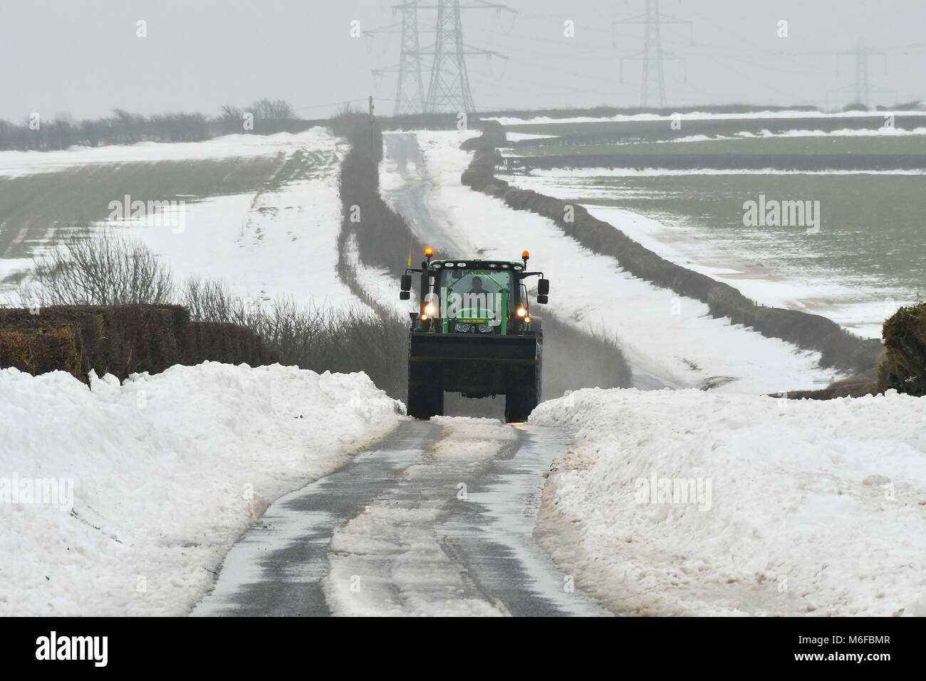 Compton Valence, Dorset, Großbritannien. 3. März 2018. UK Wetter. Ein Traktor fahren entlang der Römischen Roan in der Nähe von Compton Valence in Dorset, flankiert durch große Schneeverwehungen von Sturm Emma. Ist der Schnee zu tauen beginnt mit die meisten Felder fast Schnee frei, aber die Drifts entlang der Straßen und Plätze sind 4-5 Meter hoch. Foto: Graham Jagd-/Alamy Live News Credit: Graham Jagd-/Alamy leben Nachrichten Stockfoto