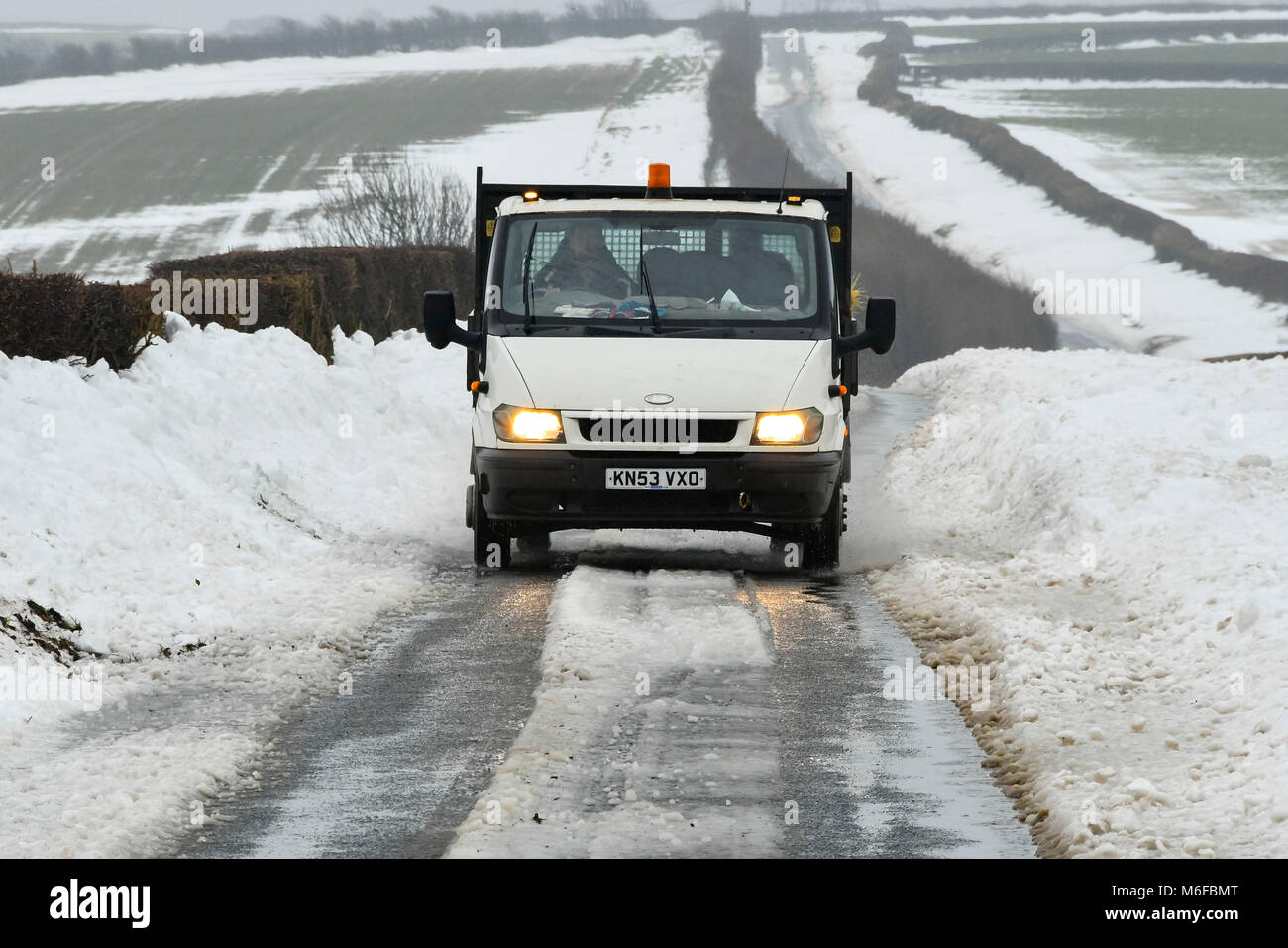 Compton Valence, Dorset, Großbritannien. 3. März 2018. UK Wetter. Ein van Fahren entlang der Römischen Roan in der Nähe von Compton Valence in Dorset, flankiert durch große Schneeverwehungen von Sturm Emma. Ist der Schnee zu tauen beginnt mit die meisten Felder fast Schnee frei, aber die Drifts entlang der Straßen und Plätze sind 4-5 Meter hoch. Foto: Graham Jagd-/Alamy Live News Credit: Graham Jagd-/Alamy leben Nachrichten Stockfoto