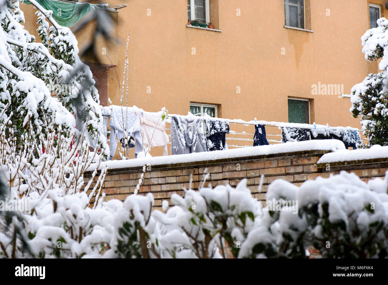 Trocknen von Kleidung hängend an einer Wäscheleine im Winter auf den Garten in der Nähe des Hauses Stockfoto