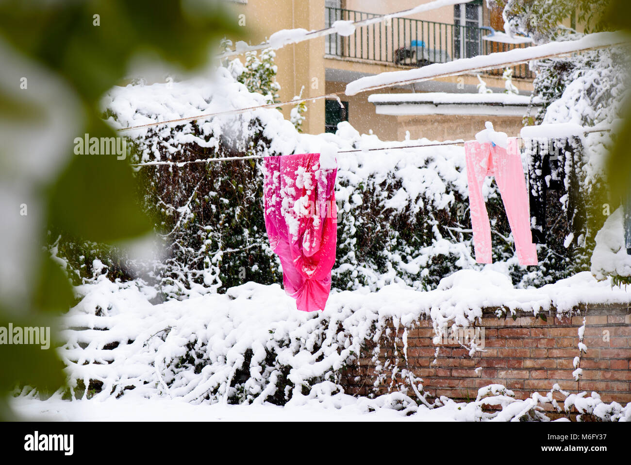 Trocknen von Kleidung hängend an einer Wäscheleine im Winter auf den Garten in der Nähe des Hauses Stockfoto