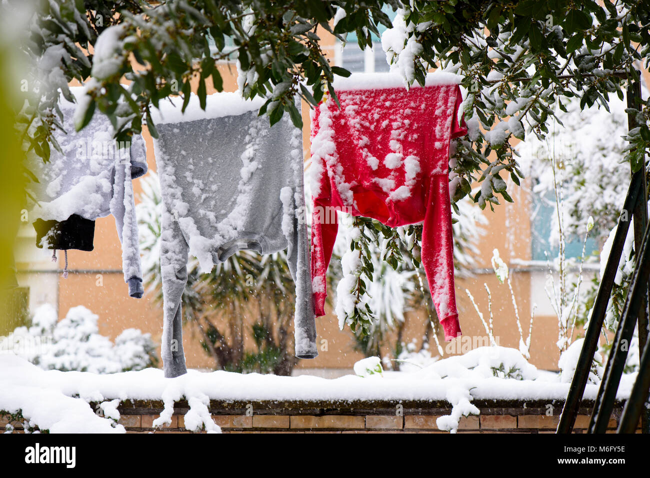 Trocknen von Kleidung hängend an einer Wäscheleine im Winter auf den Garten in der Nähe des Hauses Stockfoto