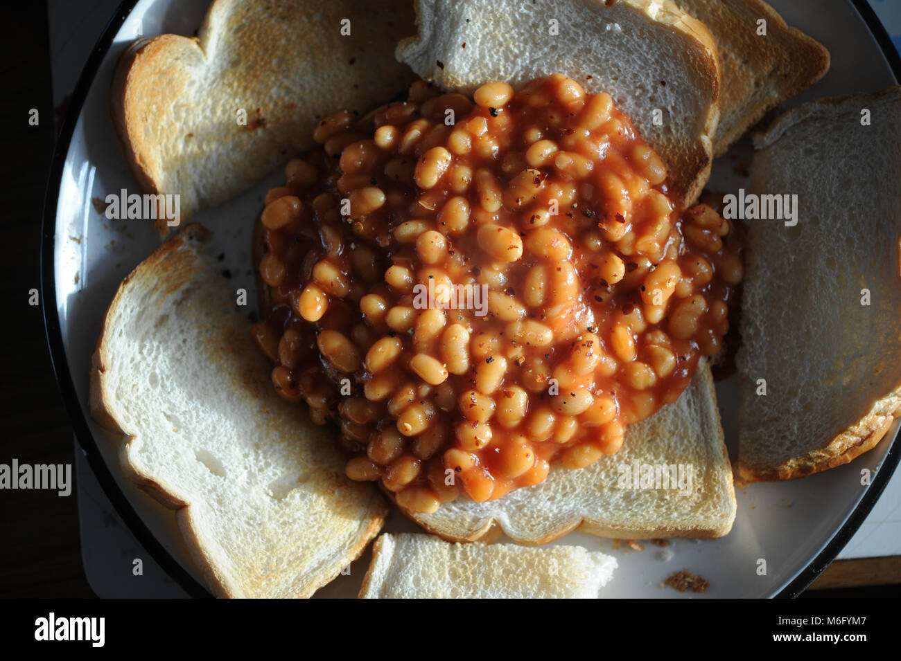 Ein Haufen von Bohnen auf Toast mit chiliflocken gestreut auf der Oberseite als Mittagssnack. Stockfoto
