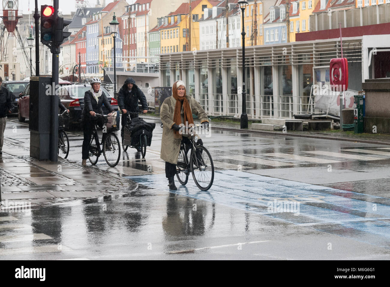 Kopenhagen - 23. Oktober 2016: Eine alte Dame und andere Menschen auf ihre Fahrräder warten die Straße während eines Regen in Nyhavn zu überqueren. Stockfoto