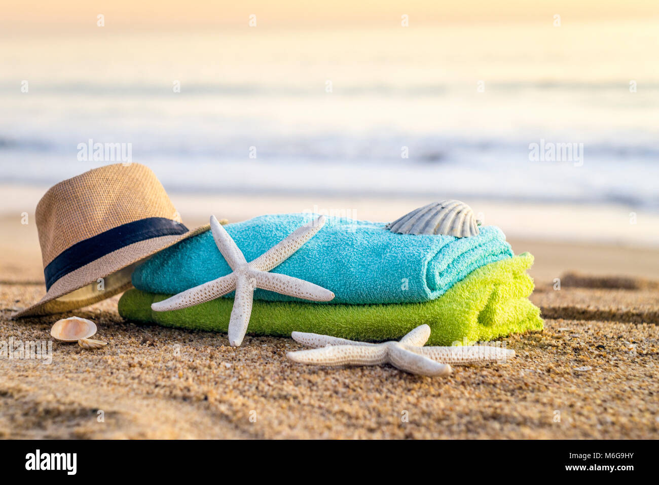 Sommer Accessoires wie Sonnenbrillen, Handtücher, Sonnenhut, Sonnencreme, Muscheln und Seesterne am Sandstrand in Portugal Stockfoto