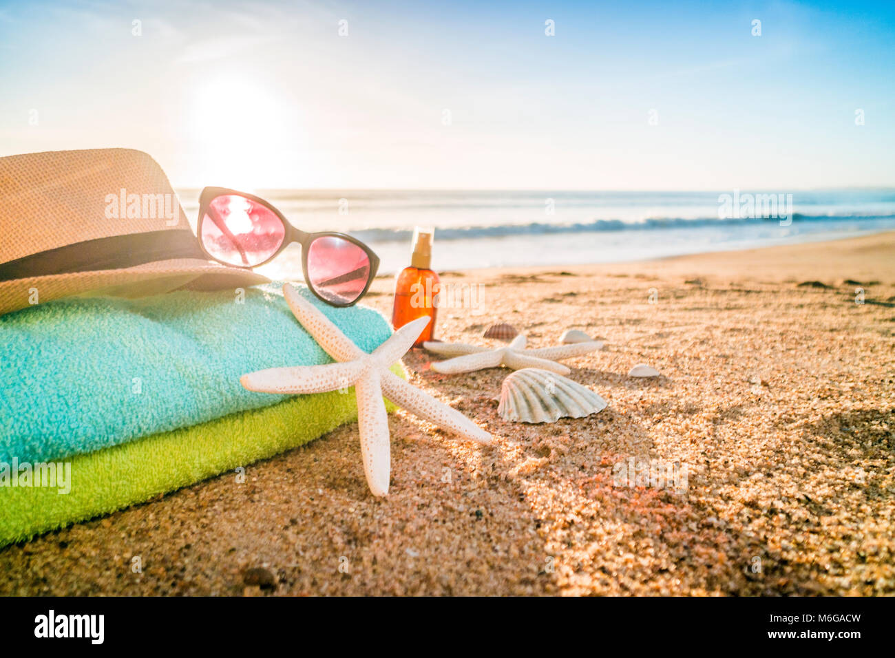 Sommer Accessoires wie Sonnenbrillen, Handtücher, Sonnenhut, Sonnencreme, Muscheln und Seesterne am Sandstrand in Portugal Stockfoto