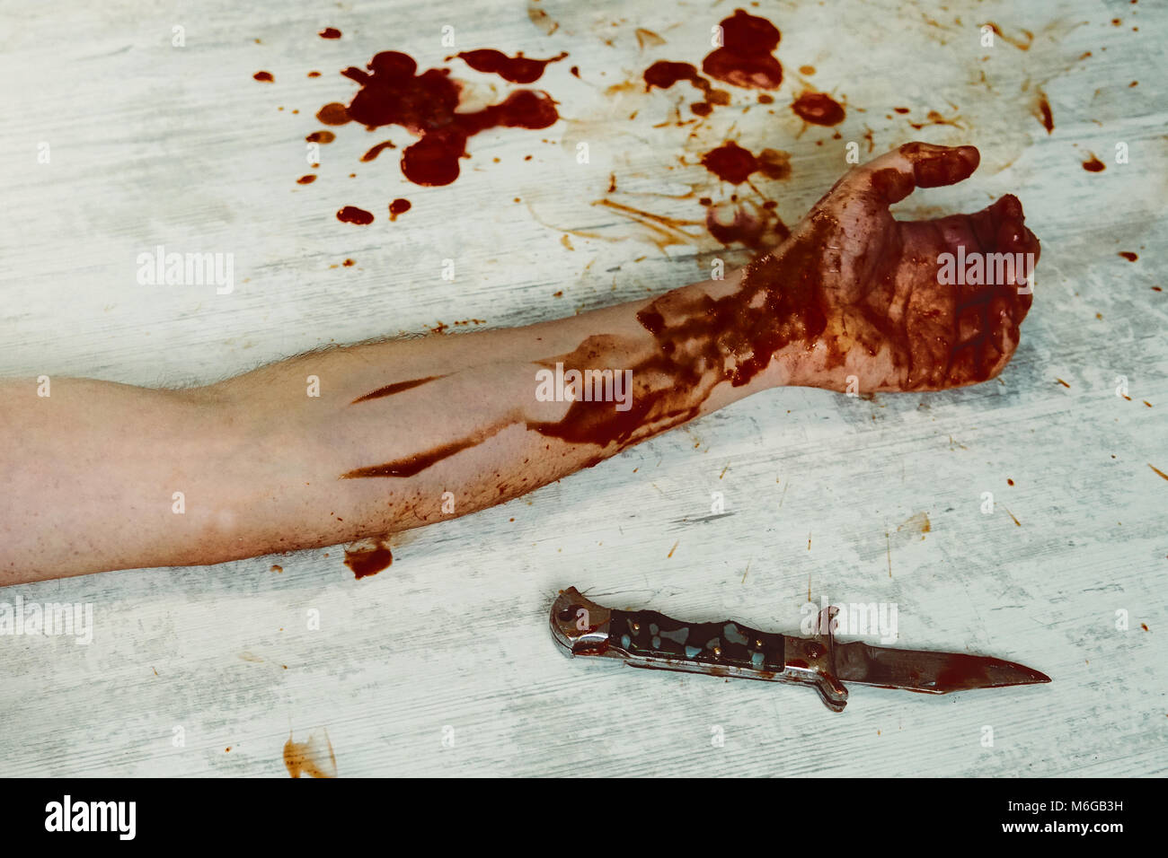 Eine blutige Hand mit einem Messer auf einem weißen vintage Holz schmutziger Boden. Das Konzept der Haushalt Verbrechen und häuslicher Gewalt. Tatort Mordopfer han Stockfoto