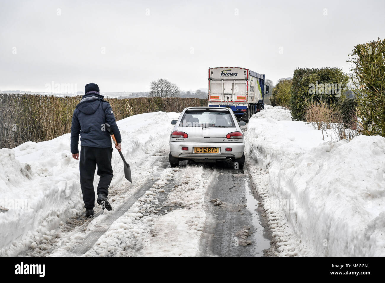 Ein Mann macht sich auf den Weg, um eingeschlossene Fahrzeuge im Schnee auf Draycott Hotel in der Nähe fest, zwischen Draycot Foliat und Ogbourne St George, in der Nähe von Marlborough, Wiltshire, wo die Straße als Ablenkung Route durch die 346 übrigen Eingeschneit verwendet wird. Stockfoto