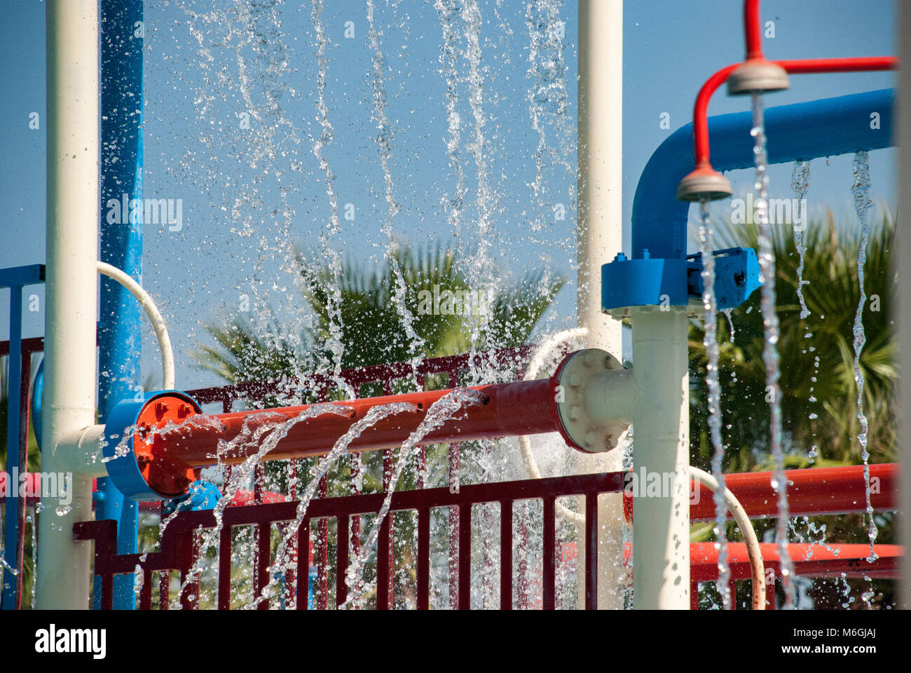 Wasserspritzer aus Geräten in einem lebhaften Kinderwasserpark mit Palmen im Hintergrund Stockfoto