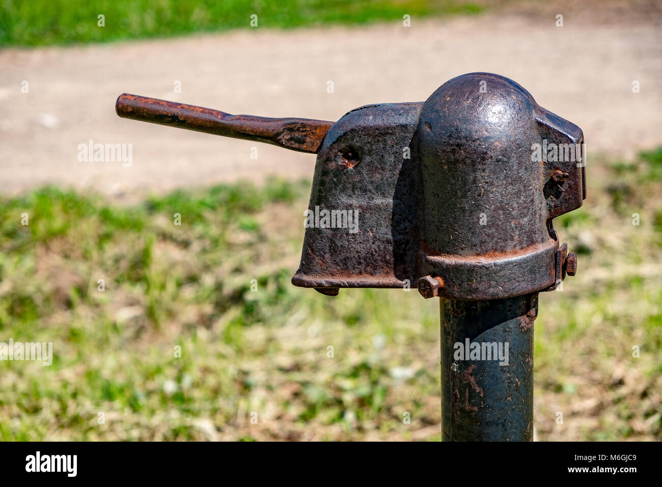 Rostige Metallkonstruktion einer alten Wasserpumpe, die in der ländlichen Straße im Sonnenlicht aufgestellt wurde Stockfoto