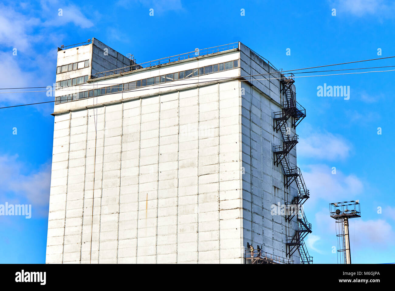 Silogebäude aus Beton mit Feuerleiter auf weißer Fassade vor blauem Himmel Stockfoto