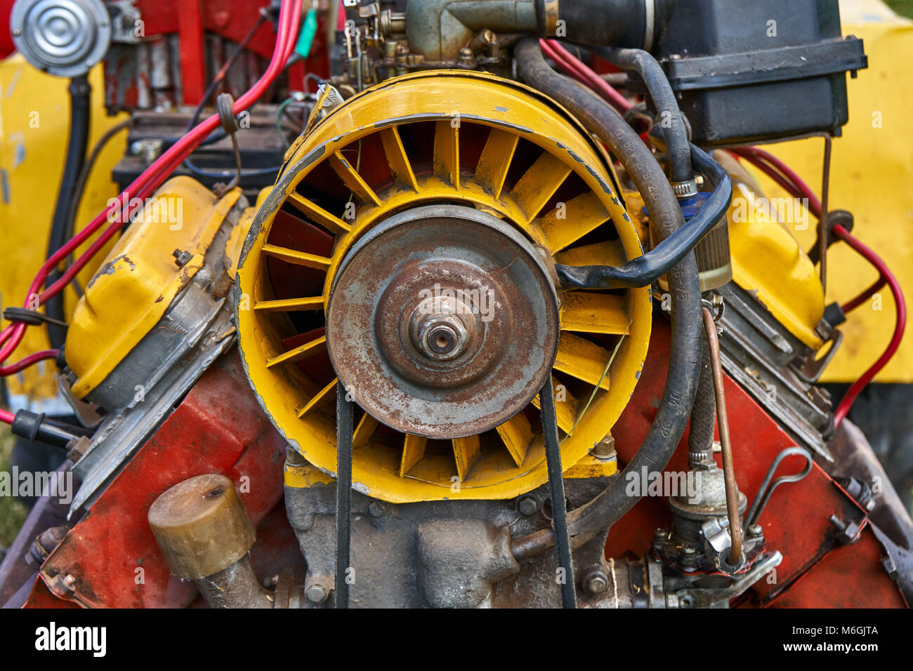 Großer heller roter Power-Traktor mit Details und Kabeln von anderen Traktoren. Motor mit nicht geschlossenen Rohren und Drähten im Nahbereich Stockfoto