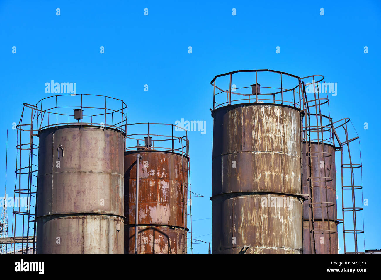 Alte rostige Industrietanktanks vor blauem Himmel Stockfoto