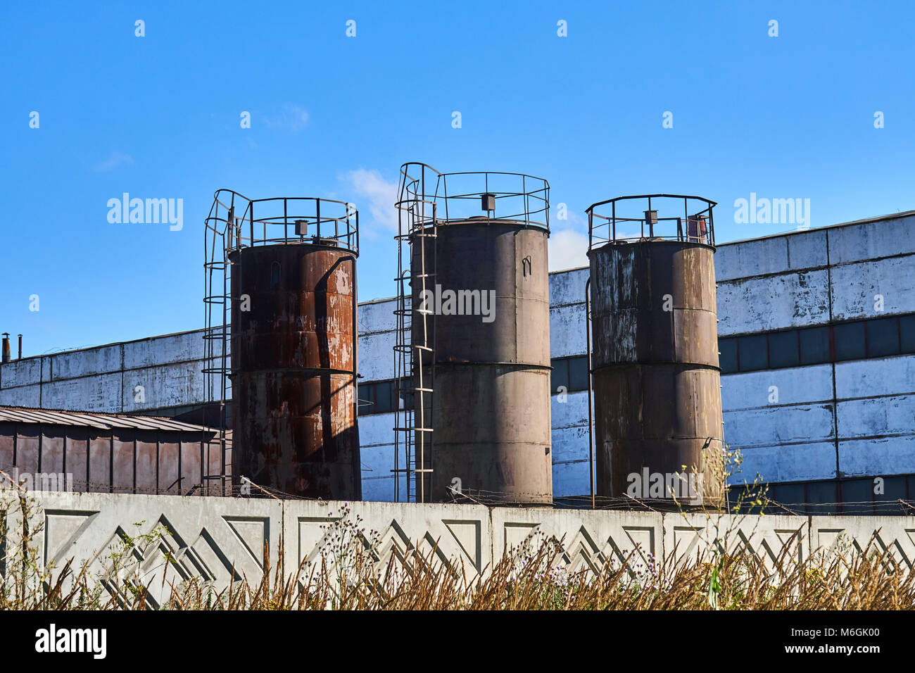 Alte rostige Industrietanktanks vor blauem Himmel Stockfoto