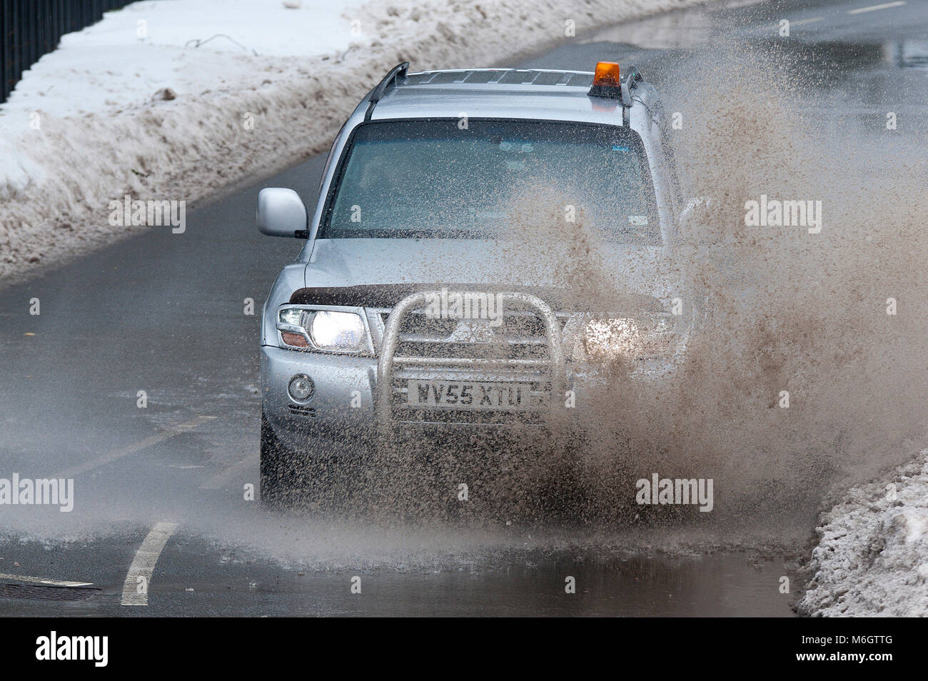 Ebbw Vale, Blaenau Gwent, South Wales, UK. 4. März, 2018. Ein Fahrzeug hits einer großen Pfütze durch schmelzenden Schnee verursacht. Nach dem entsetzlichen Blizzards, die durch Sturm Emma, in South Wales, Temperaturen jetzt gestiegen sind, Schnee zu schmelzen beginnt, und der Niederschlag ist jetzt fallende Regen in Ebbw Vale in Blaenau Gwent. Obwohl viele wichtige Straßen langsam gelöscht werden, Autos sind immer noch in Wohngebieten erfordert ein Fußweg zum Supermarkt für Lebensmittel festgefahrene. © Graham M. Lawrence/Alamy leben Nachrichten Stockfoto