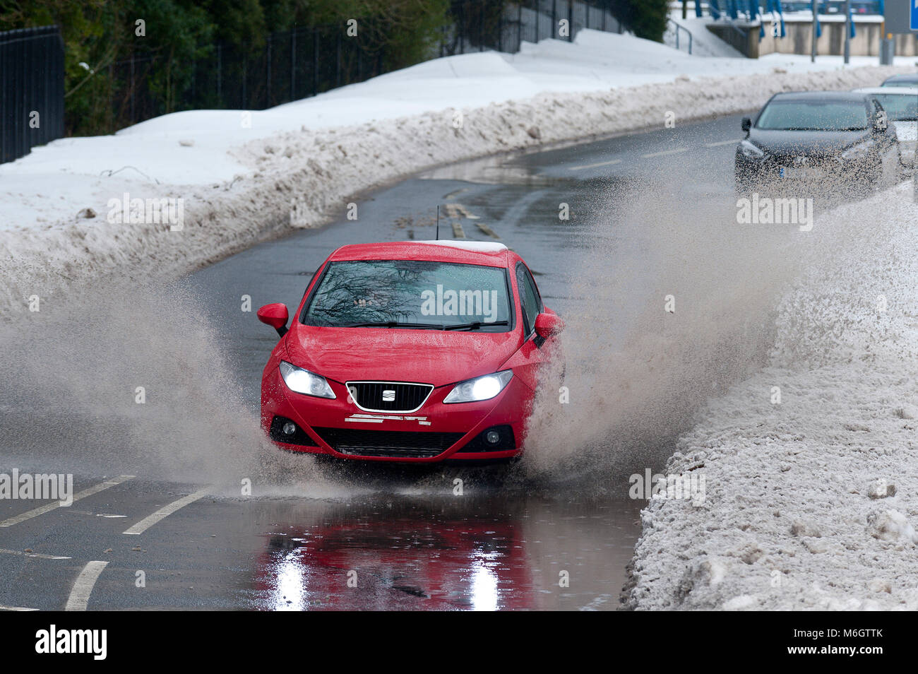 Ebbw Vale, Blaenau Gwent, South Wales, UK. 4. März, 2018. Ein Fahrzeug hits einer großen Pfütze durch schmelzenden Schnee verursacht. Nach dem entsetzlichen Blizzards, die durch Sturm Emma, in South Wales, Temperaturen jetzt gestiegen sind, Schnee zu schmelzen beginnt, und der Niederschlag ist jetzt fallende Regen in Ebbw Vale in Blaenau Gwent. Obwohl viele wichtige Straßen langsam gelöscht werden, Autos sind immer noch in Wohngebieten erfordert ein Fußweg zum Supermarkt für Lebensmittel festgefahrene. © Graham M. Lawrence/Alamy leben Nachrichten Stockfoto