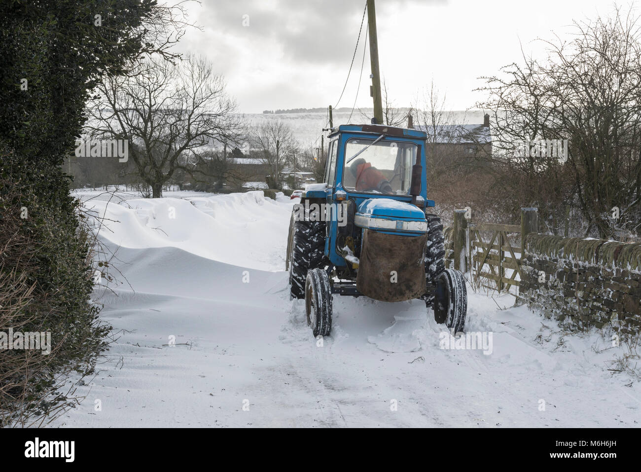 Traktor eine Straße mit tiefen Schneewehen in der englischen Landschaft freigeben, während die "Tier aus dem Osten' 2018. Stockfoto
