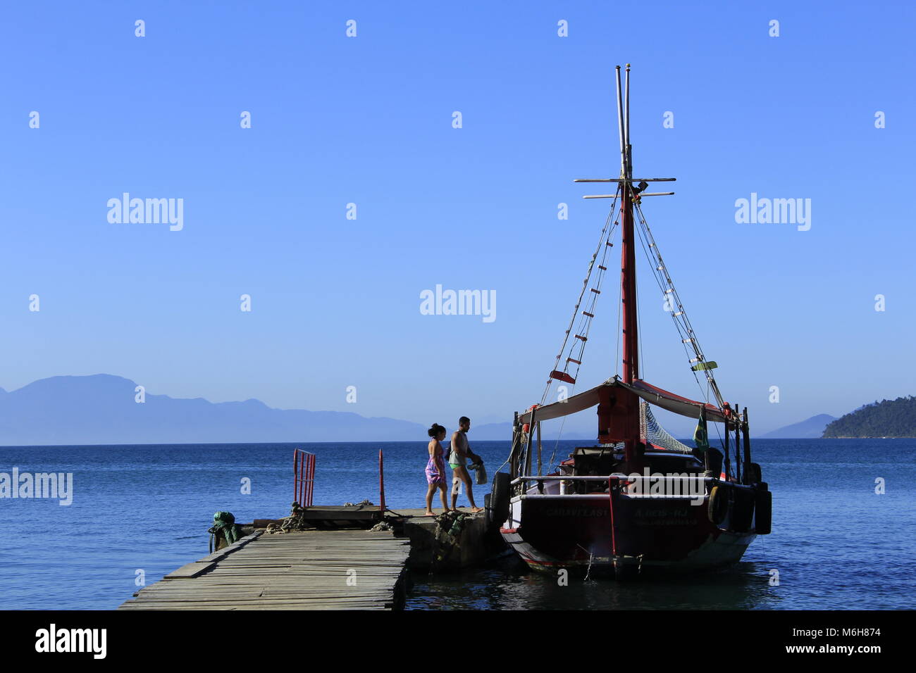 Paar Einsteigen in ein Segelboot auf einem Pier in Ilha Grande, Brasilien angedockt Stockfoto
