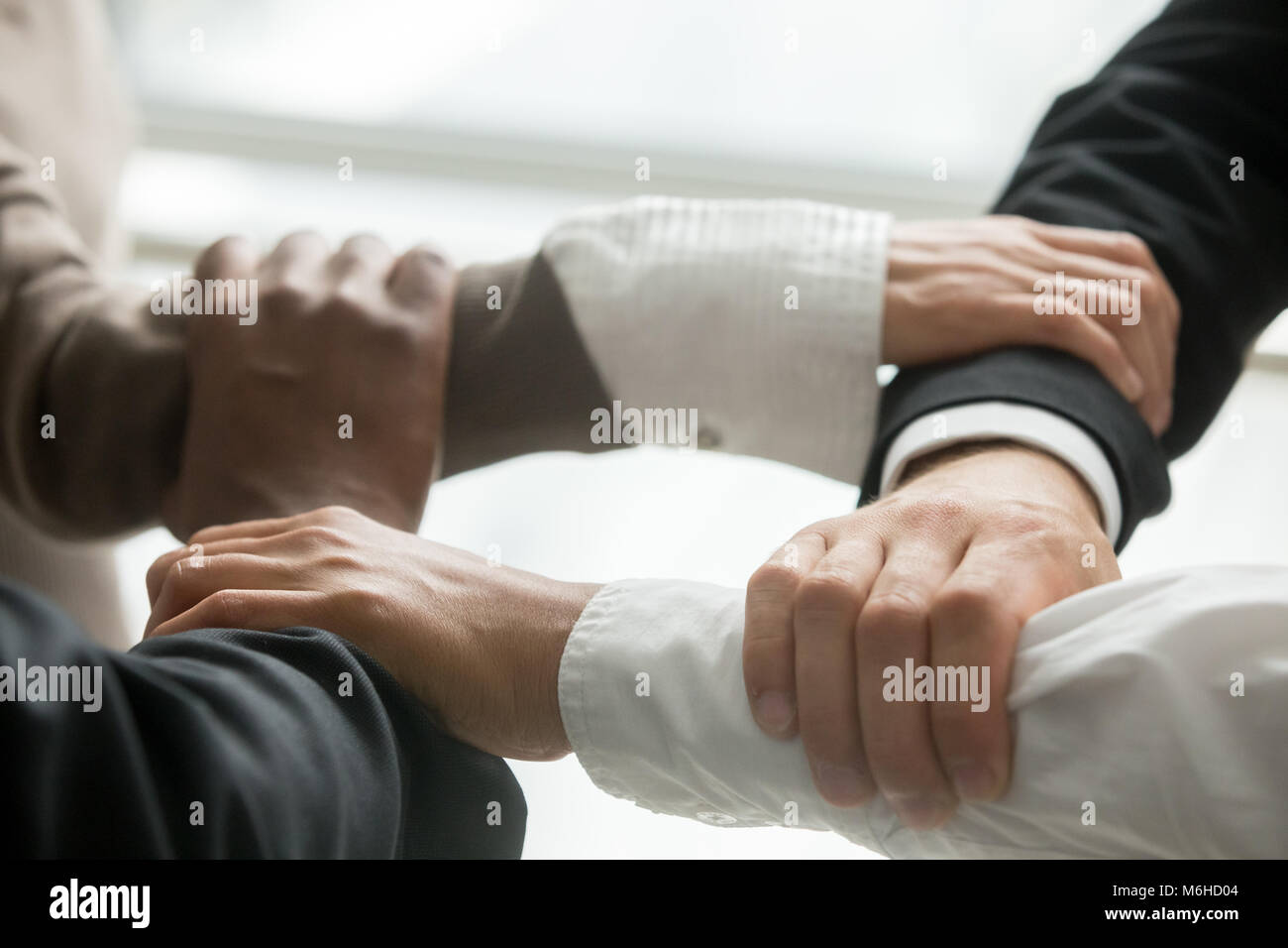 Vier multirassischen Geschäftsleute halten jedes anderen Handgelenken, Clo Stockfoto