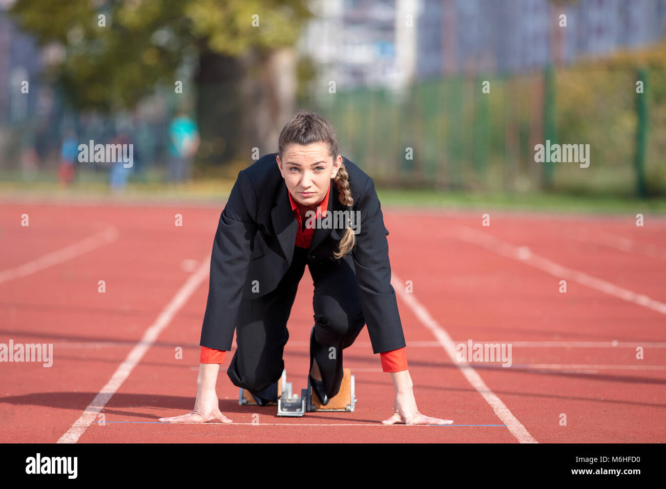 Business-Frau in Startposition ausführen und sprint auf Leichtathletik-Rennstrecke Stockfoto