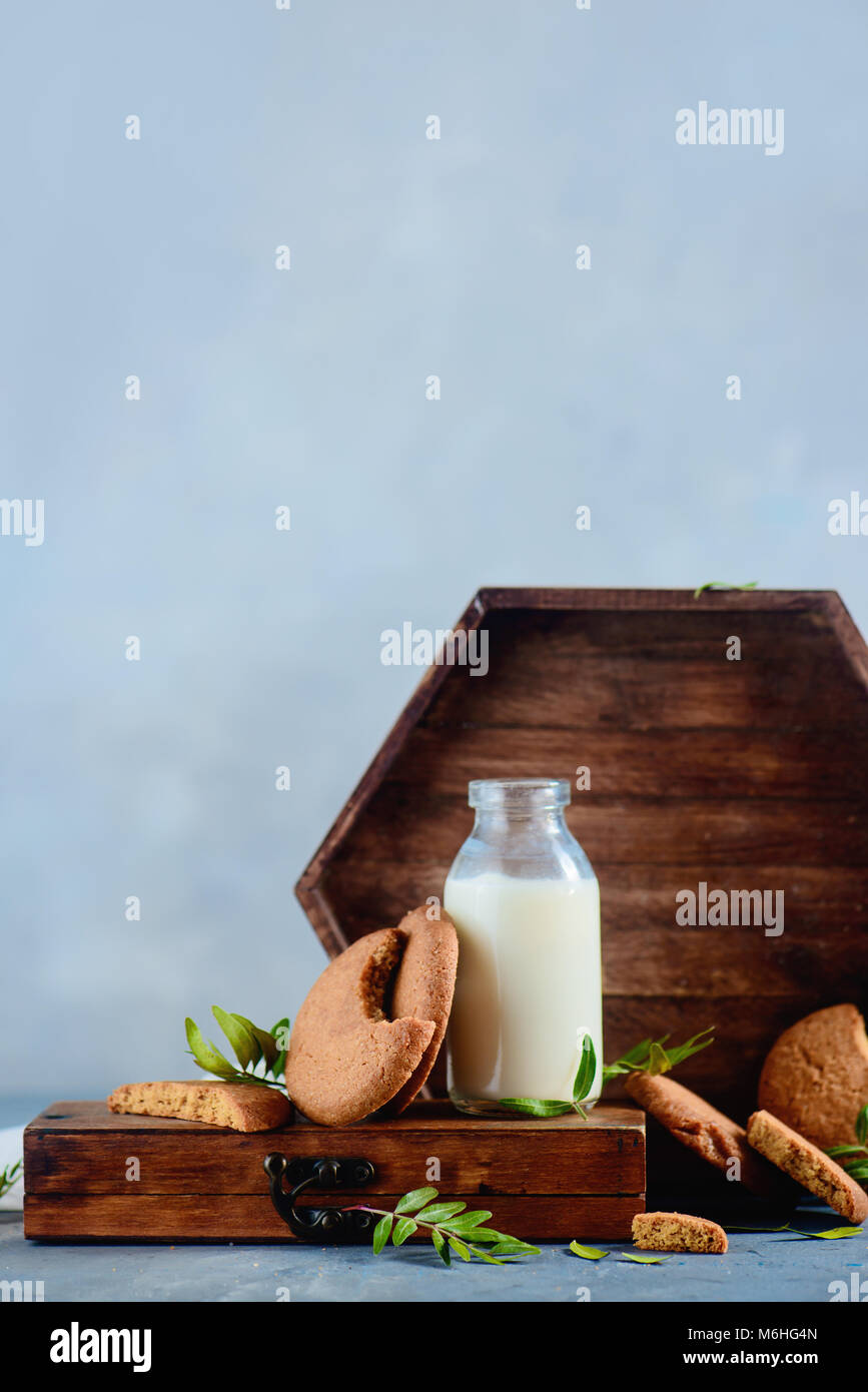Haferflocken Cookies mit einer Flasche Milch, eine hölzerne Fach und einer weißen Serviette auf einem hellen grauen Stein Hintergrund. Leckere hausgemachte Kuchen Konzept mit Kopie spac Stockfoto