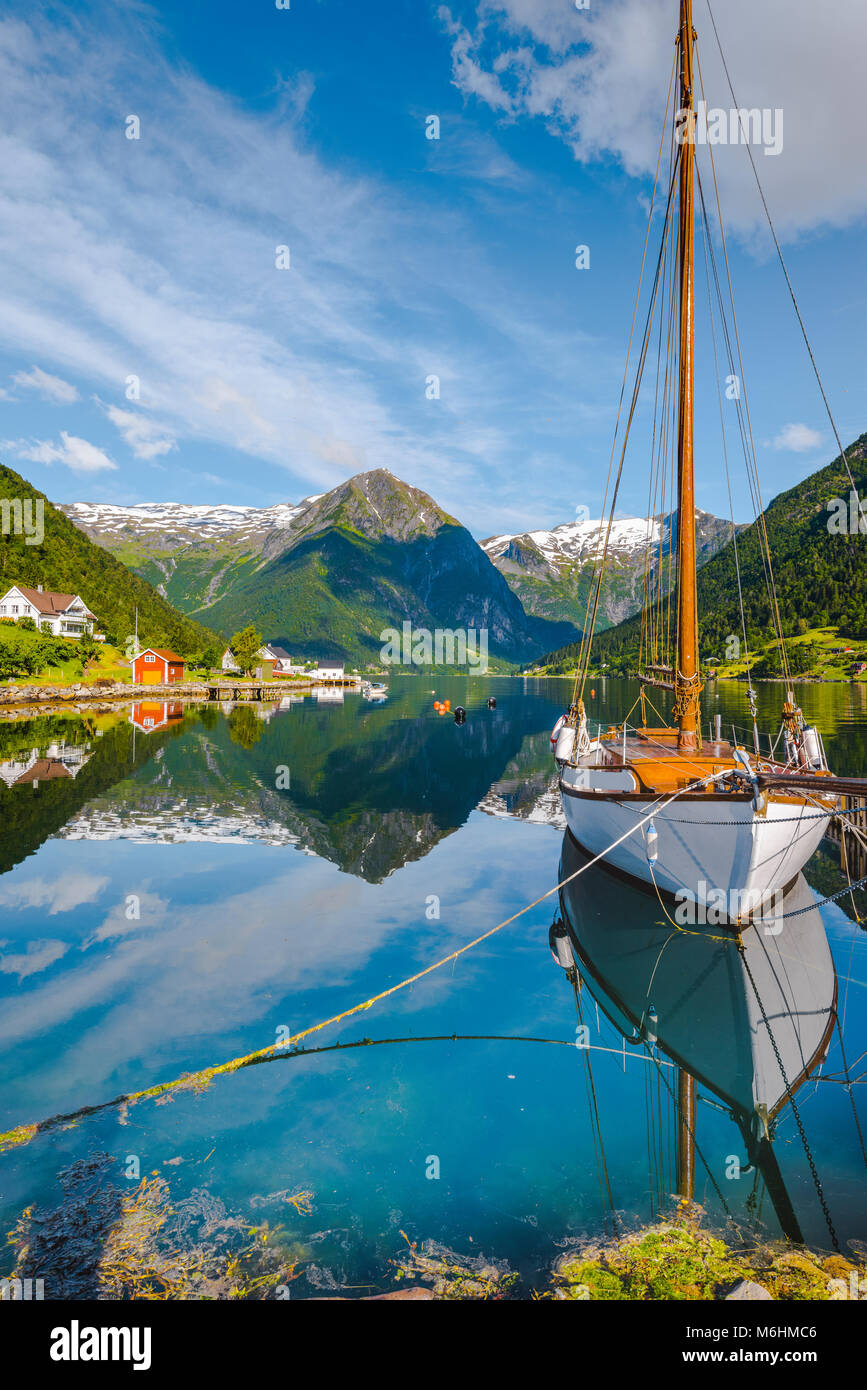 Weißes Segelboot und weißen Berge am Fjord, Bergen in Norwegen, klare Spiegelung im Sognefjorden im herrlichen Morgenlicht. Stockfoto