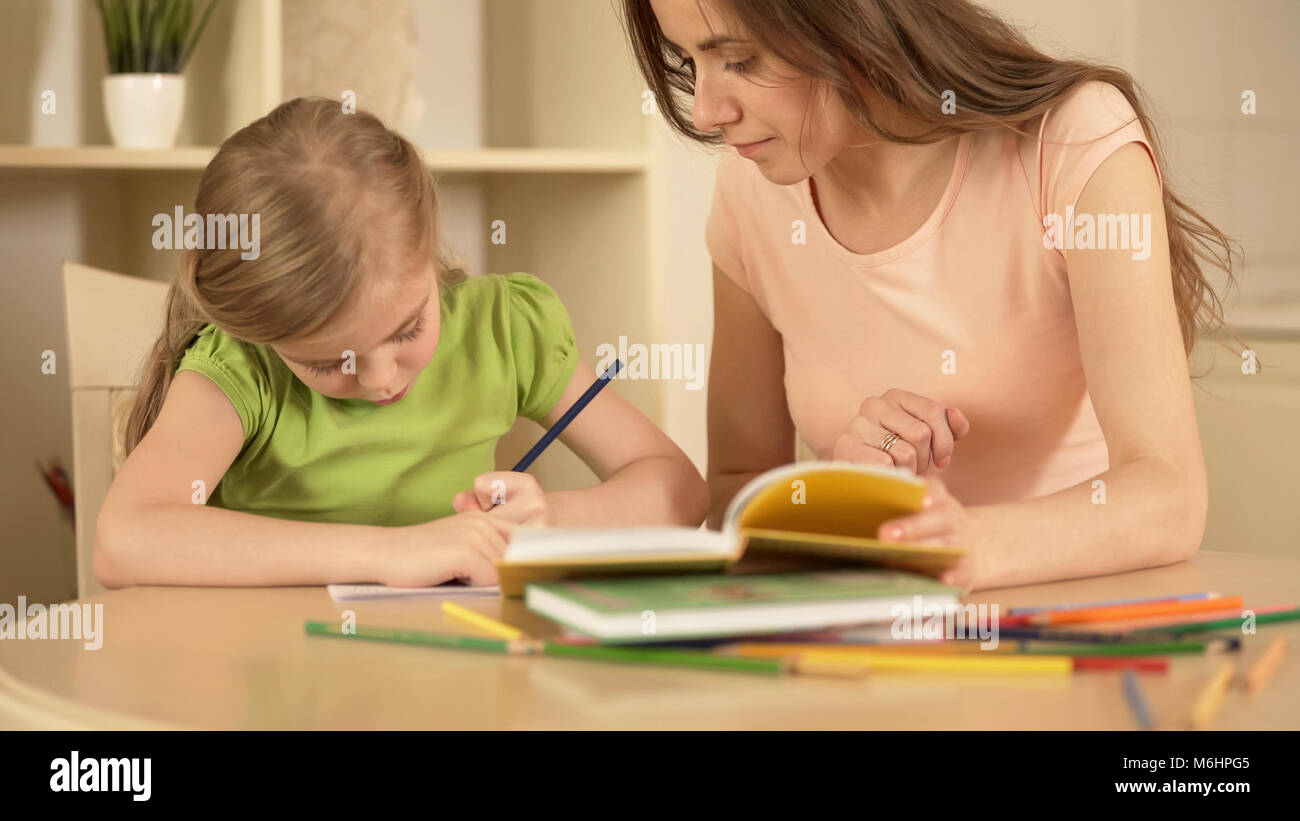 Strenge Mutter, die ihre Tochter Hausaufgaben helfen Ihr, Home Education Stockfoto