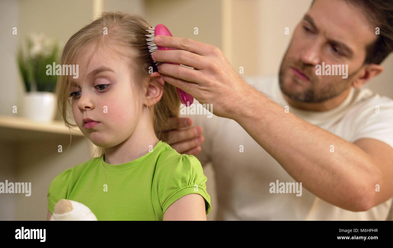 Strengen Vater zärtlich Kämmen niedlichen kleinen Töchter Haar mit ernsten Gesicht Stockfoto