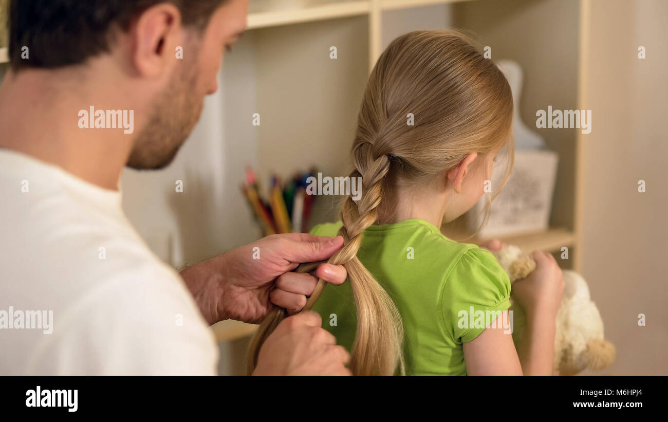 Verantwortlich guter Vater flechten kleinen Töchtern Haar, Vorbereitungen für die Schule Stockfoto