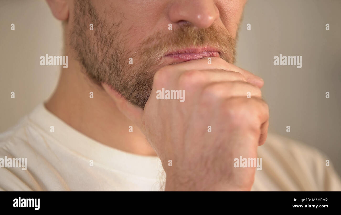 In der Nähe von schweren jungen Mann mit Bart reiben Kinn, Zweifel haben, denken Stockfoto