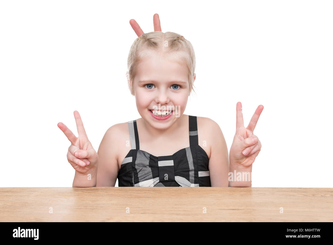 Mädchen sitzen am Tisch Hörner, mit den Händen auf weißem Hintergrund Stockfoto