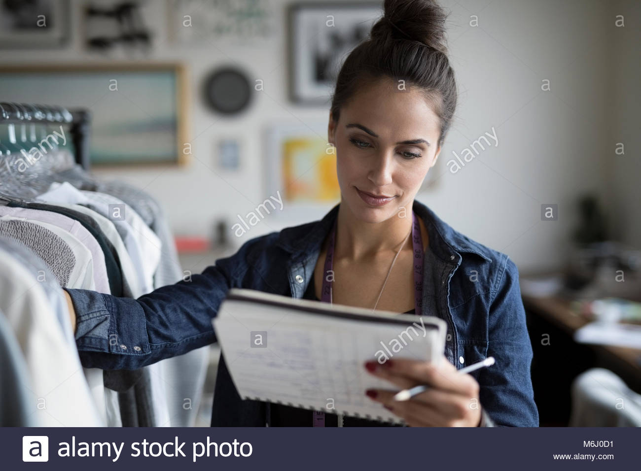Fokussierte weiblichen Kleiderschrank stylist Kontrolle Noten Kleidung Rack im Büro Stockfoto