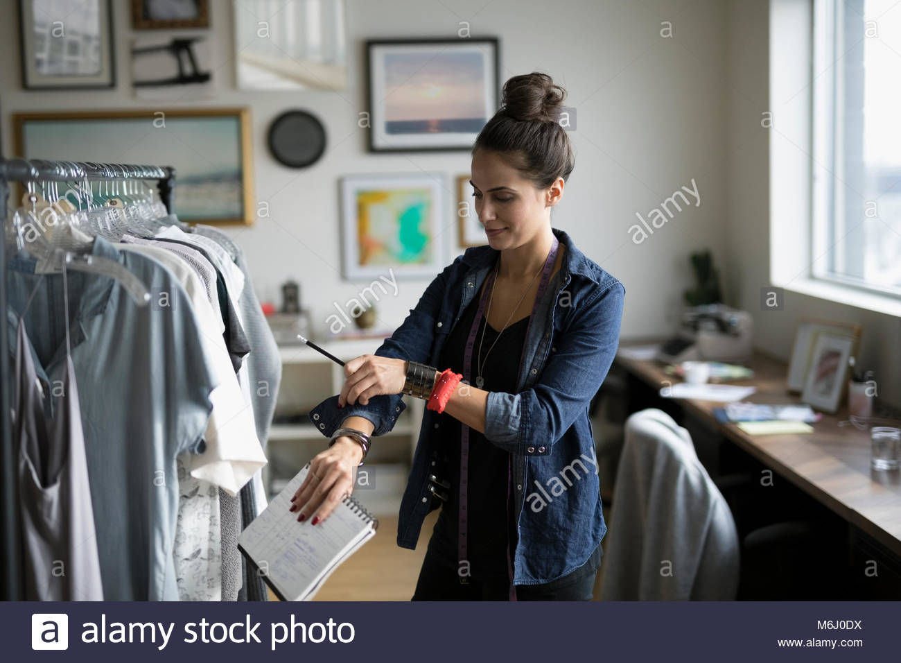 Weiblichen Kleiderschrank stylist Aufrollen Ärmel an Kleidung Rack im Büro Stockfoto