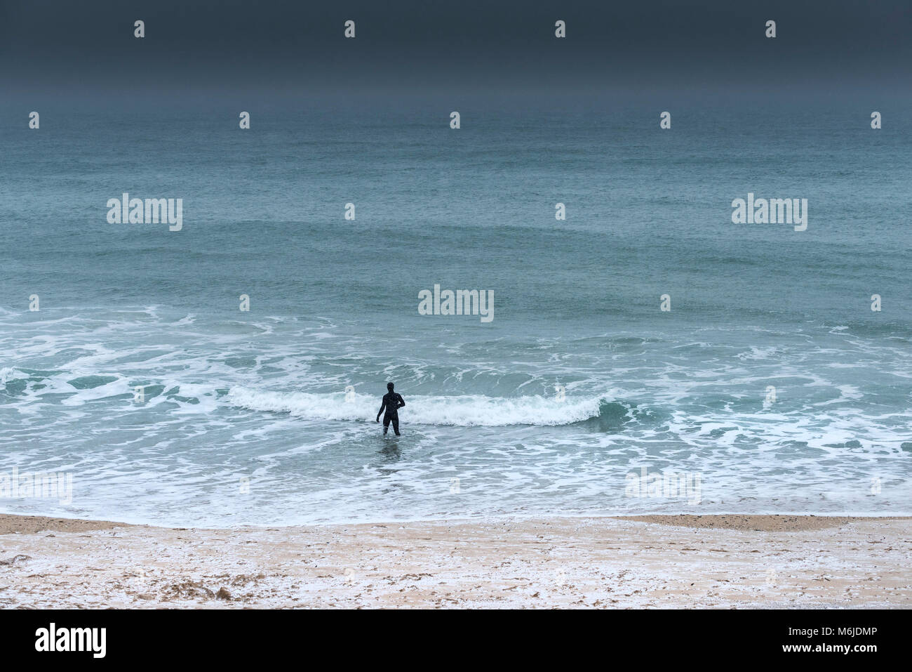 Eine Abbildung in einem Neoprenanzug zu Fuß ins Meer während eiskalt Wetter. Stockfoto