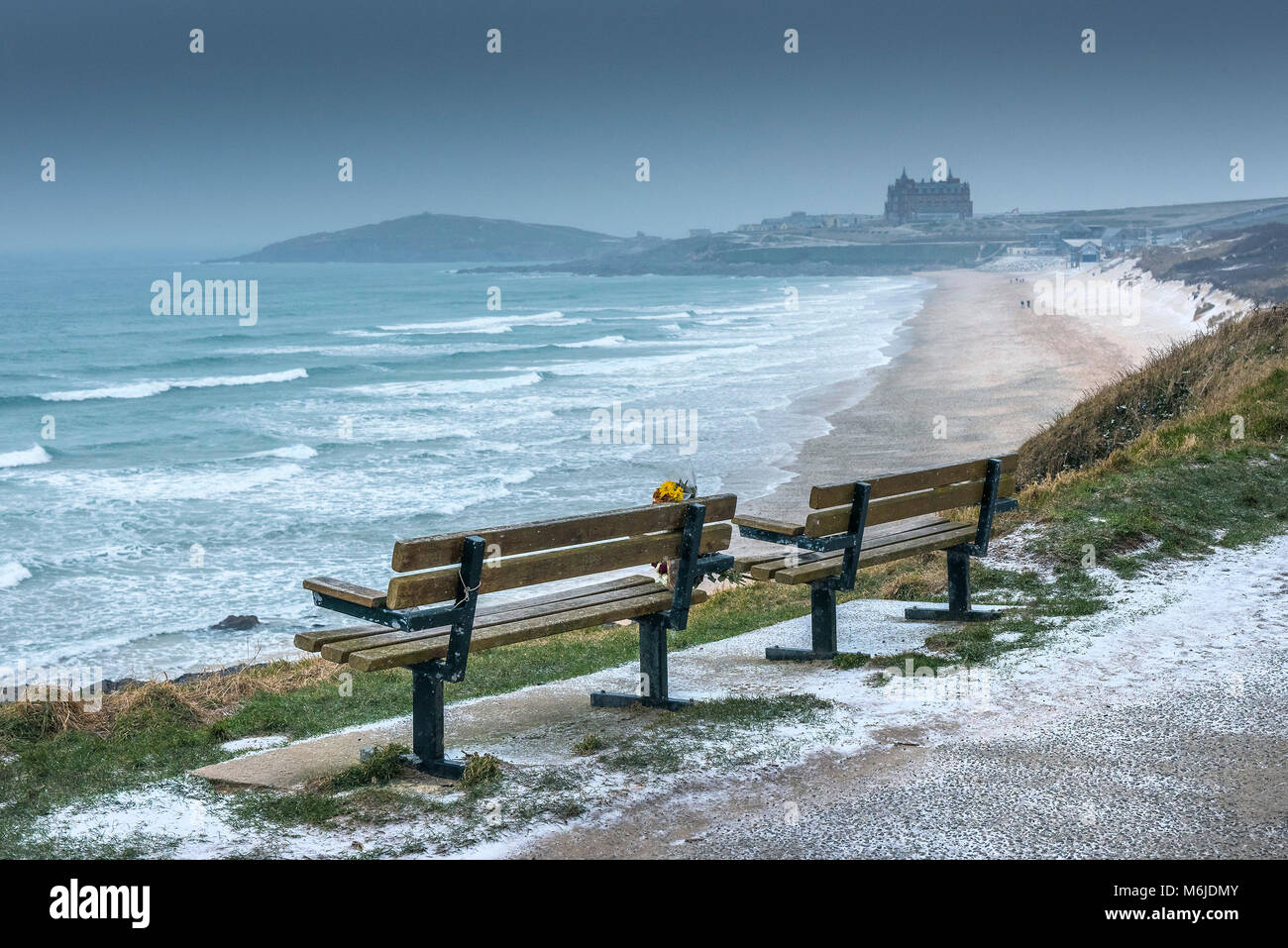 Zwei leere Sitzbänke mit Blick auf eine kalte Fistral Beach winterlichen Wetterbedingungen in Newquay Cornwall. Stockfoto