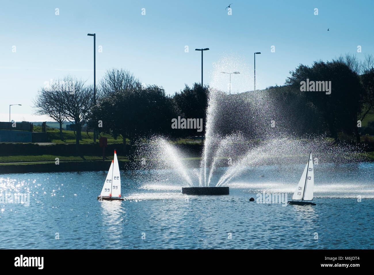 Modell Segelboote segeln hinter einem dekorativen Brunnen auf trenance See zum Bootfahren in Newquay Cornwall. Stockfoto
