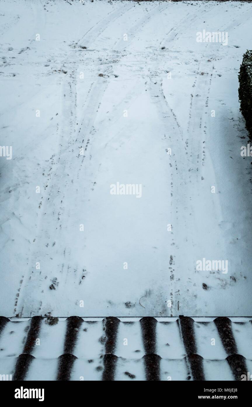Spuren von einem Auto im Schnee auf einer Fahrstraße Stockfoto