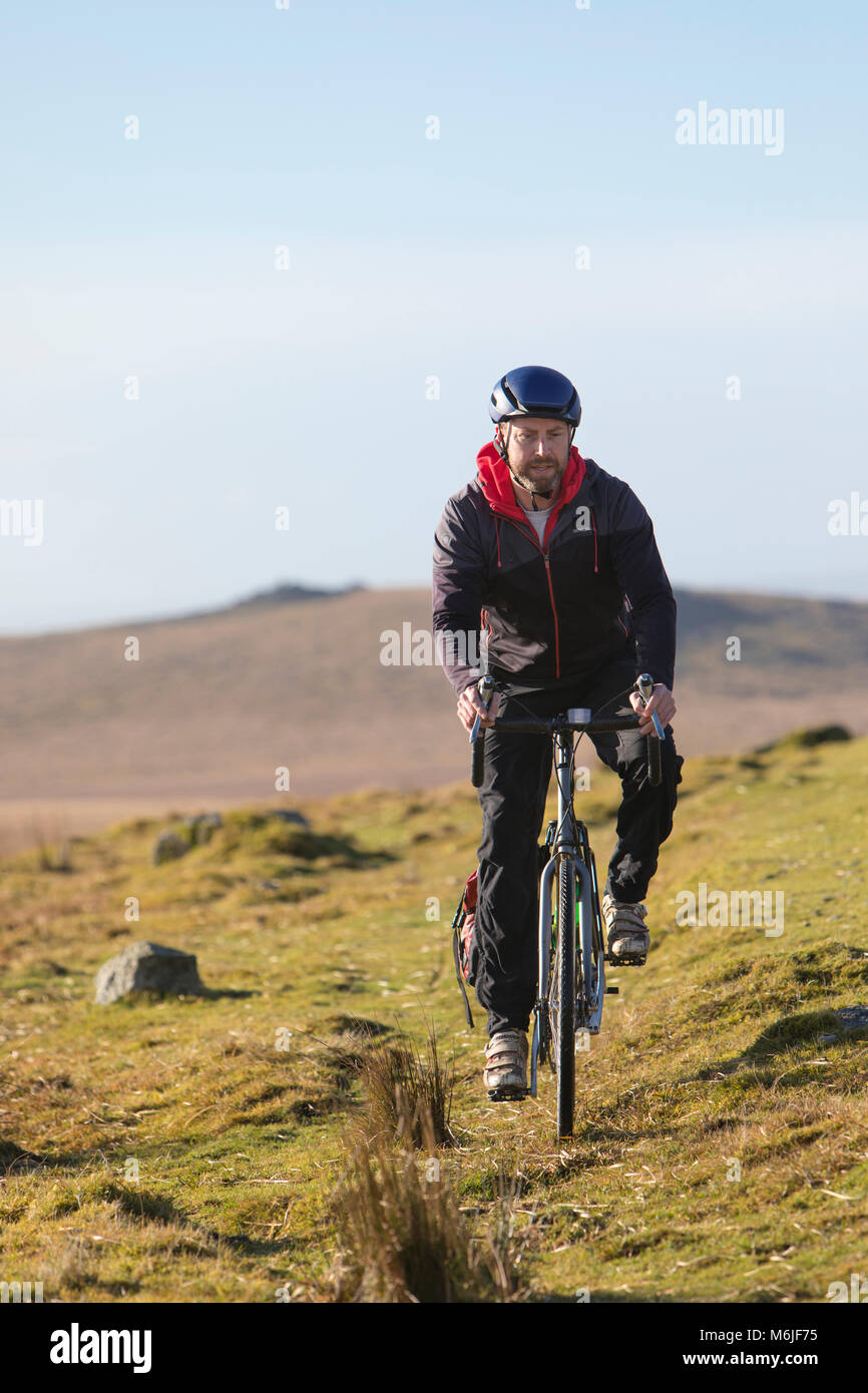 Mann fährt mit dem Fahrrad entlang einem Grat auf den Nationalpark Dartmoor, Devon Stockfoto