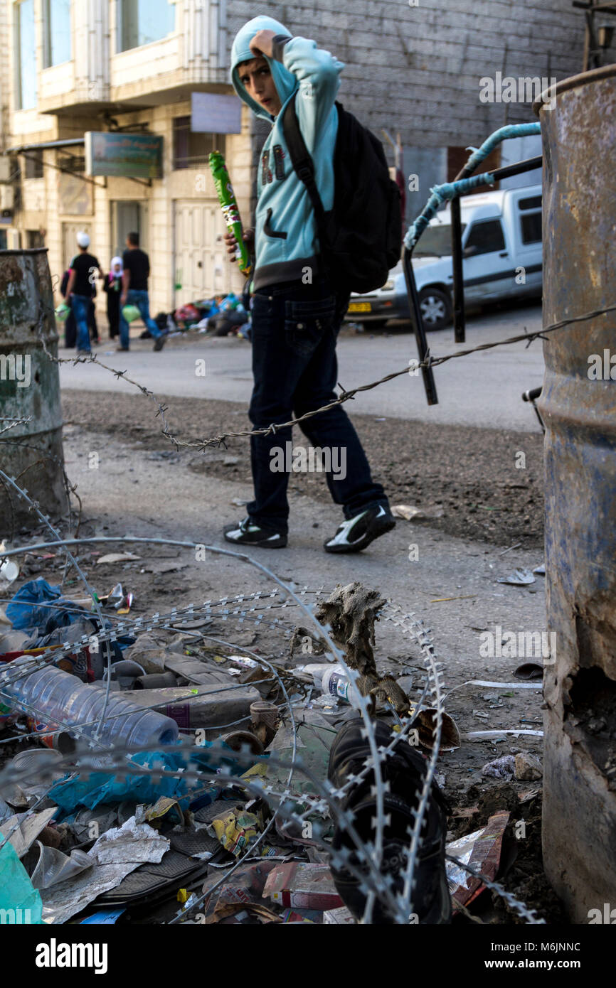 Jerusalem, Israel, November 2, 2010: Palästinensische Schüler gehen eine Straße voller dump in Shuafat Flüchtlingslager, Ost-jerusalem. Armut im Lager Stockfoto