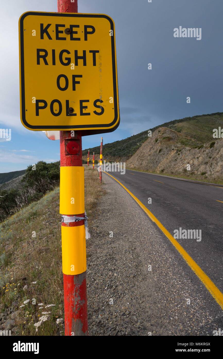 Wicklung zweispurigen Autobahn durch die australischen Alpen Region mit gelben Streifen, Kurve Zeichen roter Schnee Polen und sanften Hügeln und abgerundete Berge Stockfoto