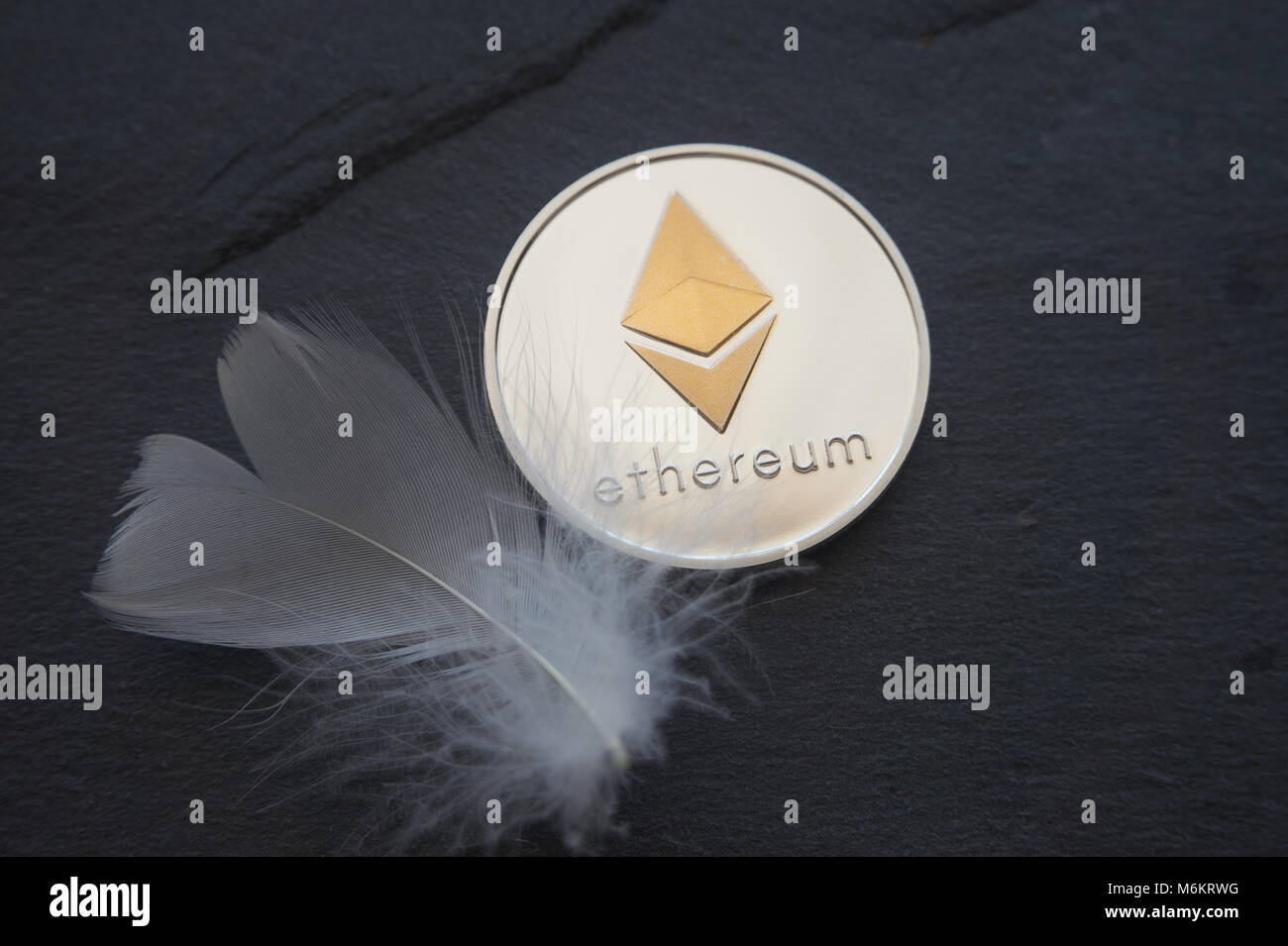 Silber Astraleums Münze liegen auf dem grauen Stein Oberfläche neben einer weißen Feder. Cryptocurrency Bergbau, Blockchain und Netzwerk Konzept, selektiver Fokus Stockfoto
